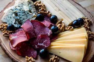 Peynir tabağı füme et, ceviz ve üzüm ahşap yüzeyi ile