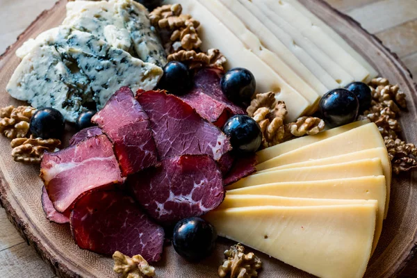 Peynir tabağı füme et, ceviz ve üzüm ahşap yüzeyi ile