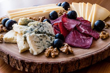 Peynir tabağı füme et, ceviz ve üzüm ahşap yüzeyi ile