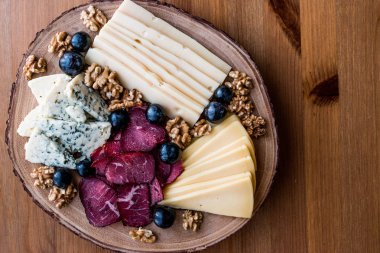 Peynir tabağı füme et, ceviz ve üzüm ahşap yüzeyi ile