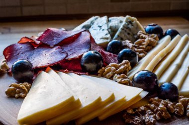 Peynir tabağı füme et, ceviz ve üzüm ahşap yüzeyi ile