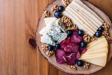 Peynir tabağı füme et, ceviz ve üzüm ahşap yüzeyi ile