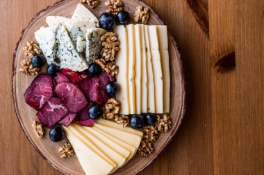 Peynir tabağı füme et, ceviz ve üzüm ahşap yüzeyi ile