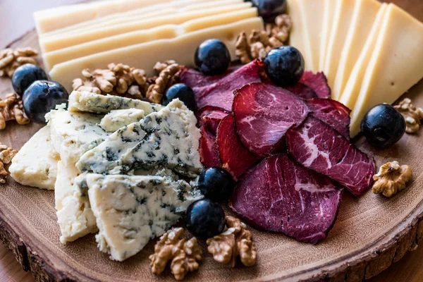 Peynir tabağı füme et, ceviz ve üzüm ahşap yüzeyi ile