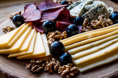 Peynir tabağı füme et, ceviz ve üzüm ahşap yüzeyi ile