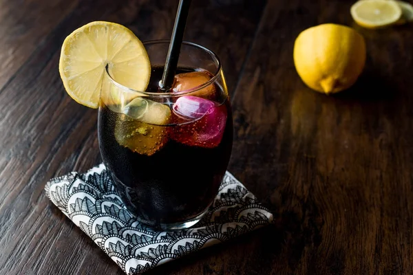 Black lemonade with charcoal, lemon and colorful bubble ice cube — Stock Photo, Image