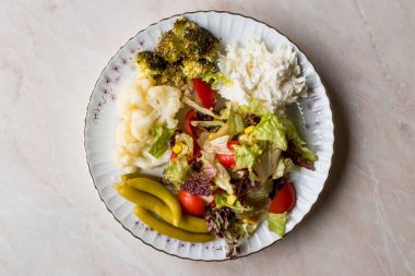 Karnabahar, kereviz, brokoli, turşu, domates ve limon ile sebze tabağı.