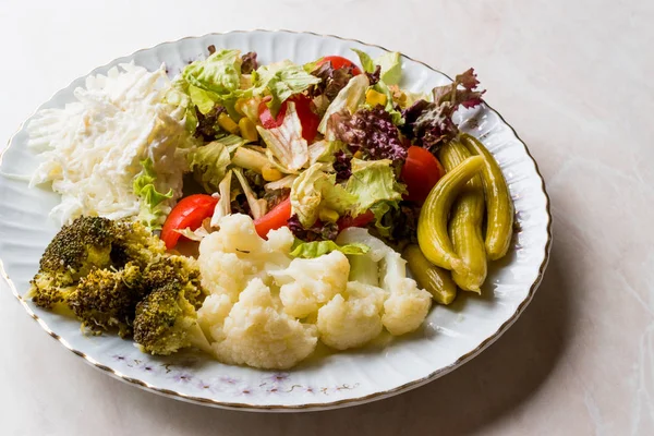 Karnabahar, kereviz, brokoli, turşu, domates ve limon ile sebze tabağı.