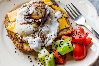 Tost ekmeği kaşar peyniri, balsamik sirke, salata ve siyah susam veya Kimyon tohumu ile haşlanmış yumurta.