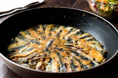 Taze kızarmış sardalye salata ahşap yüzeyi ile tavada.