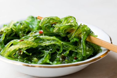 Japon Wakame deniz yosunu salata yemek çubukları ile.