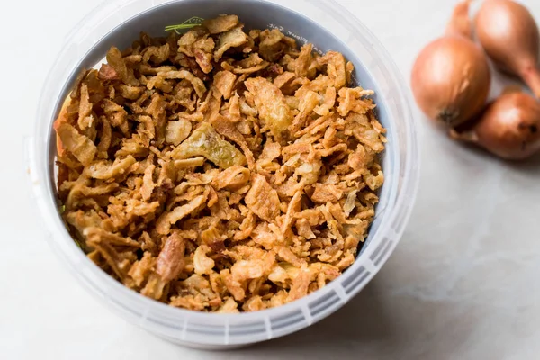 Fried Crispy Onion Flakes in Plastic Package Bowl.