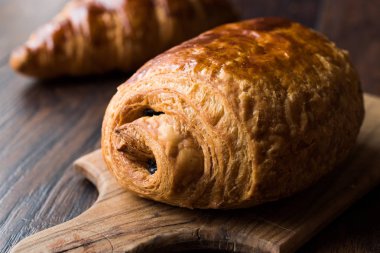 Ahşap yüzey üzerinde taze pişmiş çikolata kruvasan.