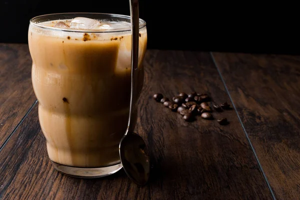 Zimna kawa rozpuszczalna z mlekiem, lód, łyżka i ziaren kawy. — Zdjęcie stockowe