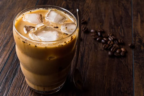 Instantní studená káva s mlékem, ledem, lžíce a kávová zrna. — Stock fotografie