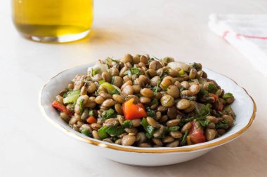 Soğan, maydanoz, domates ve seramik kase zeytinyağı ile mercimek salatası. 
