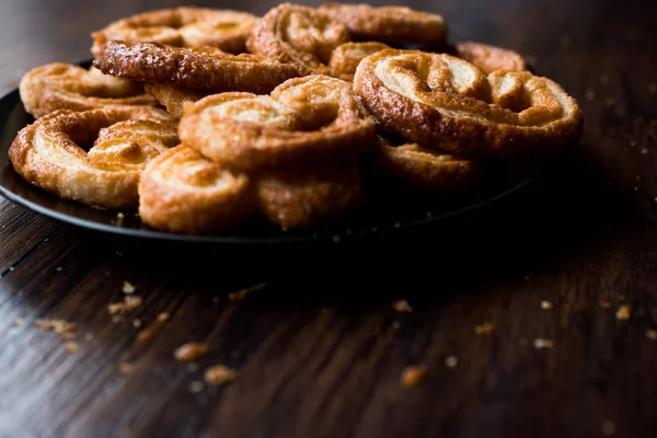 Palmier soubory cookie v černém plátu na dřevěný povrch. — Stock fotografie