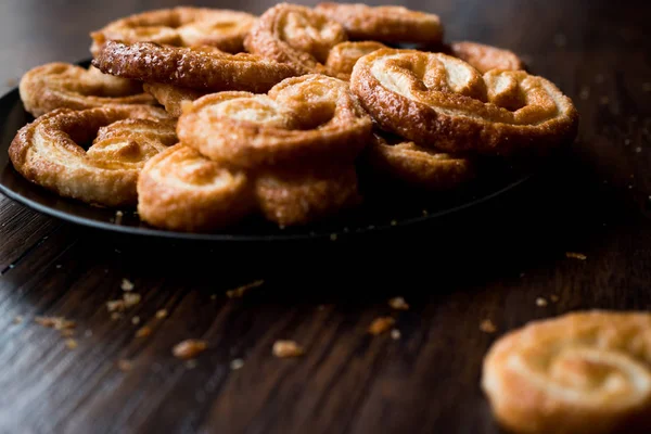 Palmier soubory cookie v černém plátu na dřevěný povrch. — Stock fotografie