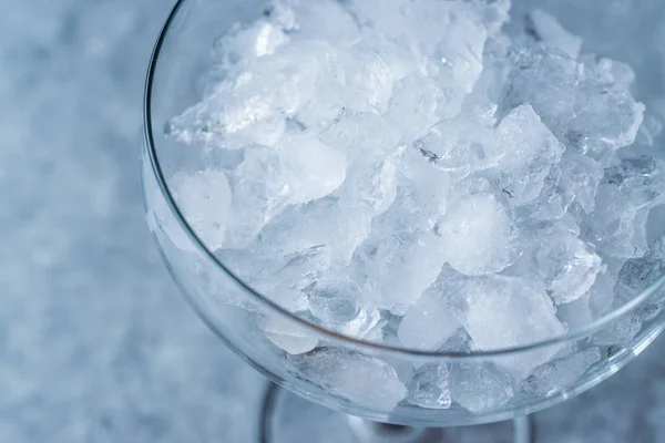 Hielo triturado en copa de cóctel en superficie azul . — Foto de Stock