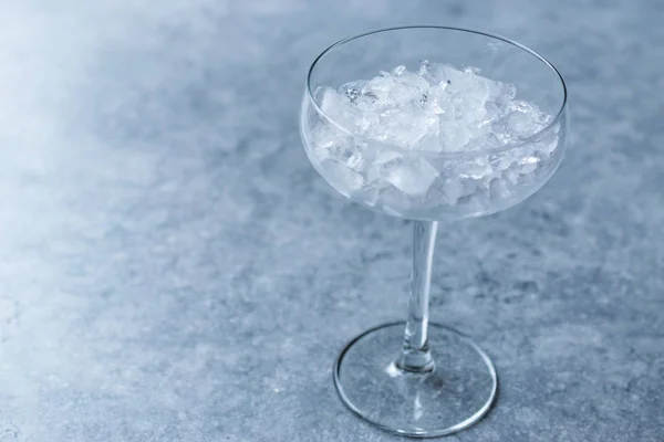 Ghiaccio tritato nel bicchiere da cocktail sulla superficie blu . — Foto Stock