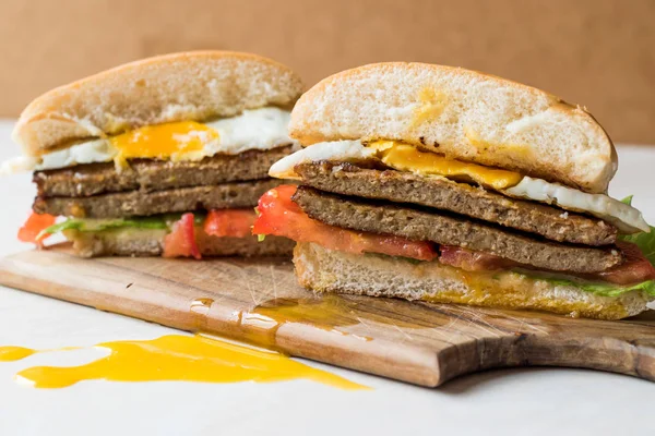Hamburger mit Ei, Tomaten und Salat auf hölzerner Fläche. — Stockfoto