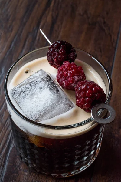 Черный / темный пивной коктейль с черными ягодами и льдом на поверхности Вудена . — стоковое фото