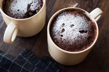 Koyu ahşap yüzey üzerinde toz şeker ile mikrodalga kek çikolata kupa pasta.