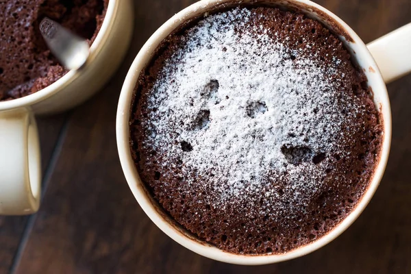 Pastel de taza de chocolate Brownie microondas con azúcar en polvo en la superficie de madera oscura . — Foto de Stock