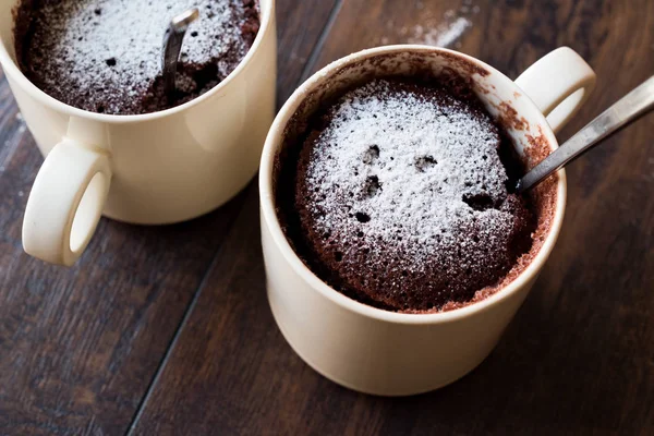 Bolo de caneca de chocolate Brownie de microondas com açúcar em pó na superfície de madeira escura . — Fotografia de Stock