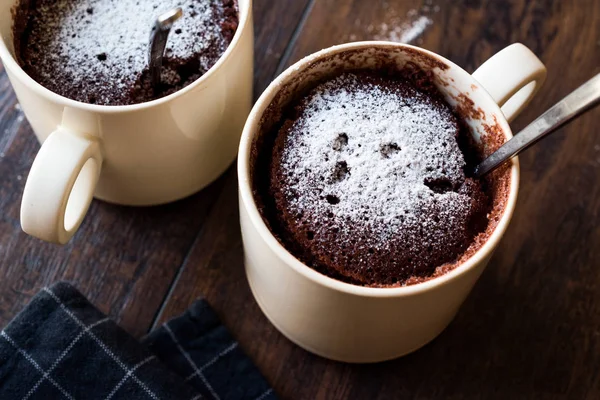 Bolo de caneca de chocolate Brownie de microondas com açúcar em pó na superfície de madeira escura . — Fotografia de Stock