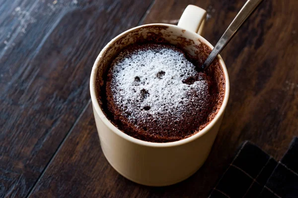 Pastel de taza de chocolate Brownie microondas con azúcar en polvo en la superficie de madera oscura . — Foto de Stock