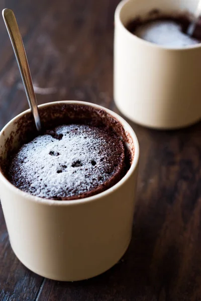 Pastel de taza de chocolate Brownie microondas con azúcar en polvo en la superficie de madera oscura . — Foto de Stock