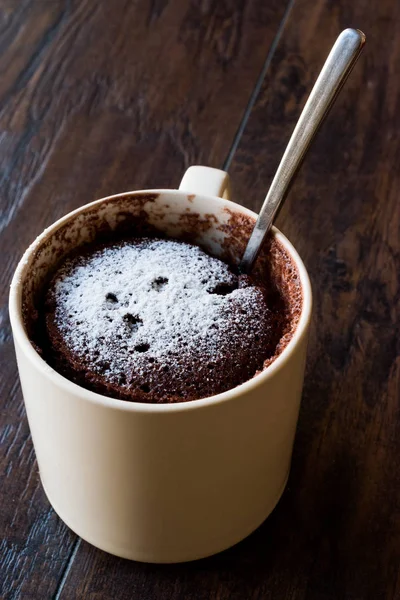 Pastel de taza de chocolate Brownie microondas con azúcar en polvo en la superficie de madera oscura . — Foto de Stock