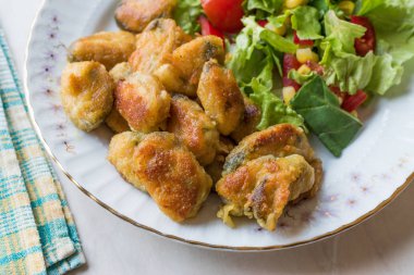 Kızarmış gevrek midye salata ile servis.