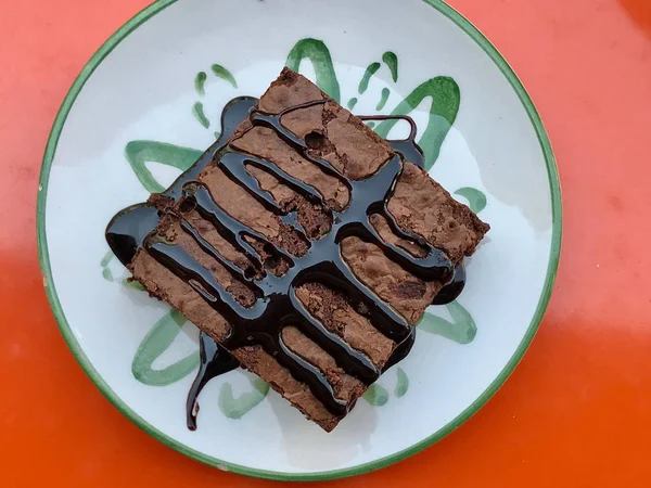 Brownie mit Schokoladensauce serviert im Café-Shop auf orangefarbener Oberfläche. — Stockfoto