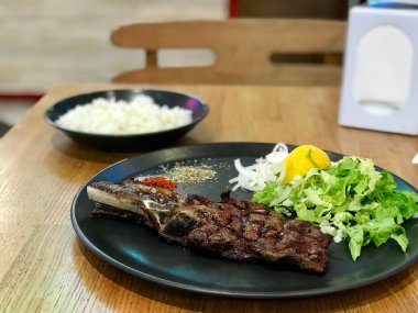 Siyah plaka büyük dana pirzola biftek salata ile servis