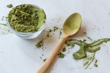 Tahta kaşık ve cam kase ile yeşil Matcha çay tozu.