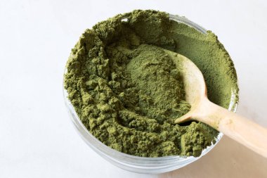 Tahta kaşık ve cam kase ile yeşil Matcha çay tozu.