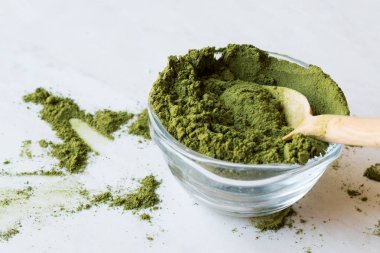 Tahta kaşık ve cam kase ile yeşil Matcha çay tozu.