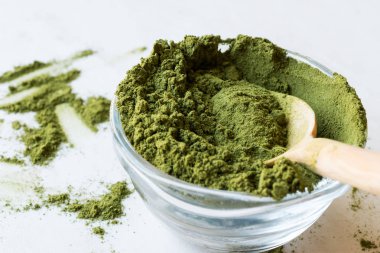 Tahta kaşık ve cam kase ile yeşil Matcha çay tozu.