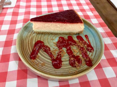 Ahududu Cheesecake kırmızı masa örtüsü üzerinde restoranda servis