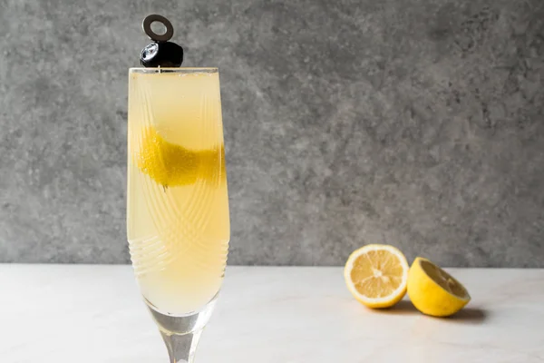 Cocktail de champanhe francês 75 com casca de limão e azeitona preta — Fotografia de Stock