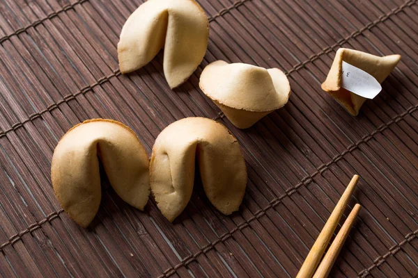 Biscotti cinesi di fortuna su tappetino di bambù con bacchette e carta — Foto Stock