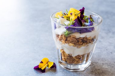 Granola parfe yoğurt ve yenilebilir çiçekler / müsli. Organik gıda.