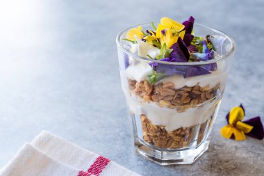 Granola parfe yoğurt ve yenilebilir çiçekler / müsli. Organik gıda.