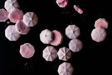 Pembe Meringues siyah yüzey üzerine pudra şekeri ile. Şekerlemeler.