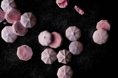 Pembe Meringues siyah yüzey üzerine pudra şekeri ile. Şekerlemeler.