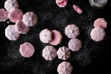 Pembe Meringues siyah yüzey üzerine pudra şekeri ile. Şekerlemeler.