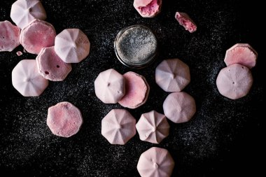 Pembe Meringues siyah yüzey üzerine pudra şekeri ile. Şekerlemeler.