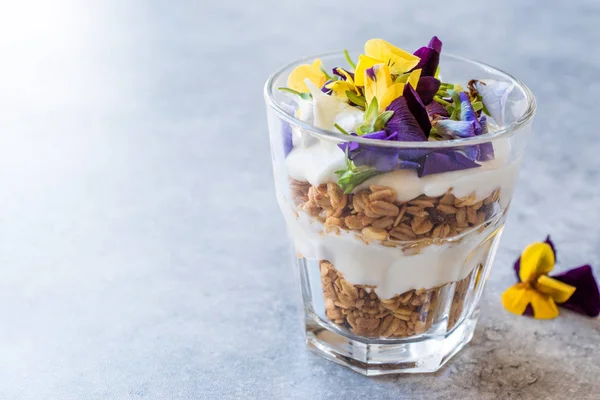 Granola parfe yoğurt ve yenilebilir çiçekler / müsli. Organik gıda.